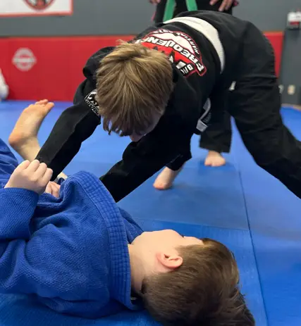 Children practicing jiu jitsu techniques during a youth class at Frequency Martial Arts in Bloomington, Illinois.